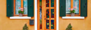 Door and windows with flowers on the yellow facade of the house