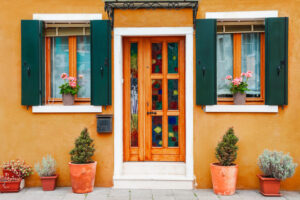 Door and windows with flowers on the yellow facade of the house