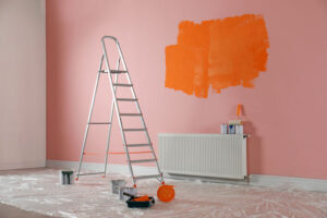 Stepladder and painting tools near wall in empty room