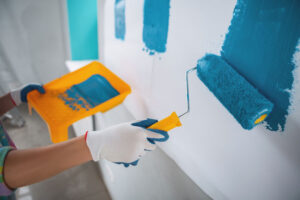 Favourite colour. Inspired young woman holding a roller and painting the walls