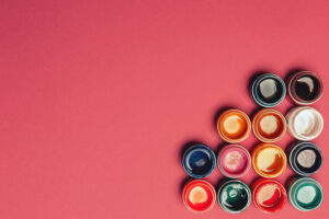 Beautiful, bright, mother-of-pearl, multicolored open cans of paint on a bright pink background. View from above. The concept of creativity.