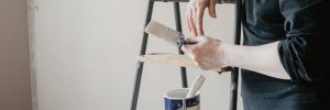 person standing near stepladder holding paintbrush in hand. home renovation concept